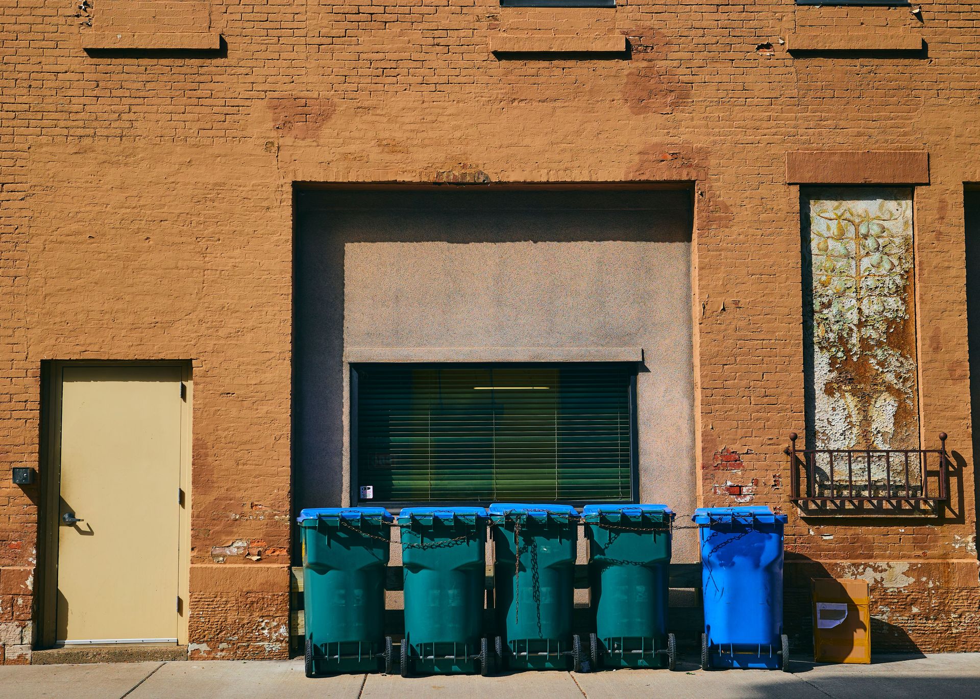 Grungy brick wall with trash bins in Rochester, NY, showcasing urban street aesthetics.